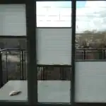 Miniaturka - Jasne plisy okienne zamontowane na oknie trzyskrzydłowym z drzwiami balkonowymi, sznurkowy system dwukierunkowy w Kobyłce.