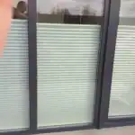 Miniaturka - Jasne rolety plisowane sznurkowe widziane od strony tarasu w ciemnej ramie okiennej, montaż w Kobyłce.