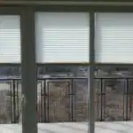 Miniaturka - Zasłonięte od góry rolety plisowane na dużym oknie balkonowym, symetrycznie ustawione osłony sznurkowe w Kobyłce.