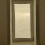 Miniaturka - Zbliżenie na biały profil aluminiowy plis okiennych zamontowany w listwie przyszybowej okna PCV.