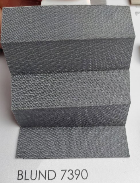 Folded gray textured fabric sample with three pleats, labeled BLUND 7390.